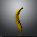 Fresh Yellow Banana Standing Upright on Black Surface with Green Sticker