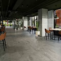 Modern Cafe Interior Design With Wooden Tables Leather Chairs Pendant Lights And Large Windows