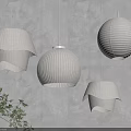 Cream Colored Paper Pendant Lights With Unique Designs Hanging On Gray Wall And Green Plant