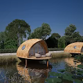 Round Floating Boutique Hotel With Thatched Roof Surrounded by Trees and Lotus
