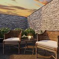 Cozy Outdoor Table With Rattan Chairs Candle And Bushes Against Stone Wall At Sunset