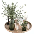 Green Ribbed Vase Holding Olive Branches On Wooden Tray With Black Statue And Candle