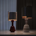 Two Modern Table Lamps With Red And Textured Bases And Metallic Shades On Light Table