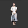 Woman in white T-shirt and colorful long skirt with sandals against gray background