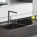 Stainless Steel Kitchen Sink With Faucet Water Flowing And Yellow Apples On Black Countertop