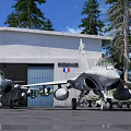 Military Fighter Jets Parked In Front Of White Hangar With French Flag And Pine Trees