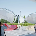 White Tensile Membrane Structure In Outdoor Park Landscape With People Enjoying Greenery