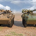 Two Tan And Green Armored Tanks On Sandy Terrain Under Blue Sky White Clouds