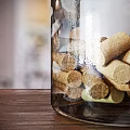 Transparent Glass Candle Lamp With Lit White Candle And Cork Decorations On Wooden Tabletop