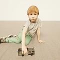 Young Boy With Red Hair Sitting On Light Floor Holding Toy Car In Gray T Shirt Green Pants
