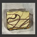 Delicious Square Layered Cake with Vanilla Cream and Chocolate Drizzle on White Paper