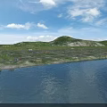 Serene Lakeside Natural Scenery With Calm Blue Water Green Hills White Clouds And Pebbled Shore