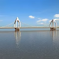 Modern Landscape Bridge Spanning Water With Unique Pylons Under Blue Sky And White Clouds