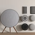 Round Gray Speaker on Wooden Stand with Wall Mounted Speakers Various Shapes Colors