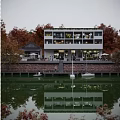 Waterfront Commercial Street with Modern Building Autumn Trees Outdoor Seating and Boats