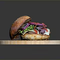 Freshly Prepared Hamburger On Wooden Cutting Board With Sesame Bun Lettuce Red Onion And Sauce