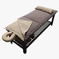 Massage Bed with Black Frame Gray Beige Blanket Pillows and Lower Shelf Stacked Towels