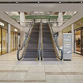 Shopping Mall Lobby With Dual Escalators Storefronts And Tile Flooring Under Ceiling Lighting