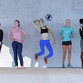 Group of Women with One Jumping to Hit Volleyball and Others Standing