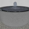 Garden Courtyard Round Stone Fountain With Textured Design And Water Feature On Gravel Surface