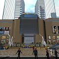 Modern Commercial Complex Featuring Glass Curtain Wall Entrance Tall Buildings Plaza Pedestrians Billboards and Fountains