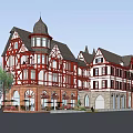 Red White Half Timbered Commercial Complex With Gabled Roofs Multi Story Retail Spaces And Greenery