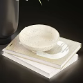 White Tulips in Black Vase with Green Leaves and White Bowl on Stacked Books
