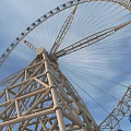 Amusement Park Ferris Wheel With Metal Structure And Blue Cabins Against Blue Sky