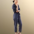 Woman in navy blue jumpsuit with long sleeves and pockets standing against neutral background