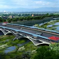 Modern Bridge With Red Canopies Over River And Scenic Mountain City Landscape