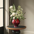 Red Glazed Vase with White Blooms and Greenery on Round Wooden Table in Interior
