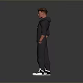 Man Standing in Black Hoodie and Pants with Hands in Pockets White Sneakers Gray Background