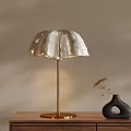 White Petal Shaped Table Lamp With Gold Base On Wooden Table And Black Vase