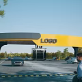 Modern Entrance Gate With Yellow And Gray Structure LOGO Vehicles Trees And Parking Area