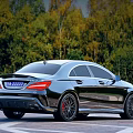 Modern Black Sedan Car With Red Rims Parked On Road Near Green Trees