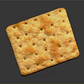 Golden square cracker with small holes and orange spots showing surface texture on gray background