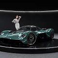 Green Sports Car Displayed on Circular Platform with Elegant Woman in Modern Exhibition Hall