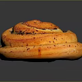Golden Brown Swirl Baked Pastry Topped With Poppy Seeds On Dark Surface