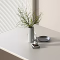 Green Branches In White Vase On White Table Near Window Blinds With Small Plate