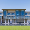 Modern Townhouse Exterior With Large Glass Windows Balconies And Green Lawn