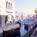 Scenic Commercial Street with White Arched Buildings Water Canal Gondola Boats and Pedestrians