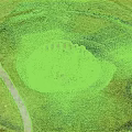 Ancient Stone Circle Structure with Wooden Elements in Lush Green Grassland Area