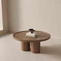Round Wooden Coffee Table With Two Cylindrical Legs Topped With White Book And Black Bowl