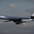 Silver Fighter Jet Flying With Extended Landing Gear In Cloudy Sky