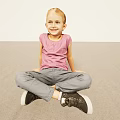 Smiling Woman Sitting On Floor Wearing Pink Top Gray Pants And Black Shoes