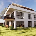 Modern Detached Villa With White Exterior Large Windows Balcony Green Lawn And Outdoor Furniture