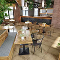 Open Space Restaurant With Wooden Ceiling Hanging Green Plants Pendant Lights And Red Brick Walls