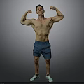 Shirtless Muscular Man Flexing Muscles In Blue Shorts And Green Sneakers Against Gray Background