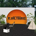 Feature Wall With Orange Circle Text Surrounded By Plants Tables Chairs And Teepee In Garden