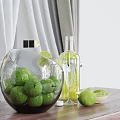 Spherical Glass Bowl With Green Limes And Transparent Wine Bottle On Wooden Table Curtain Background
